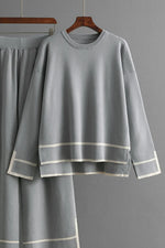 Gray outfit with white trim on a hanger against a gray background
