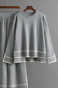 Gray outfit with white trim on a hanger against a gray background
