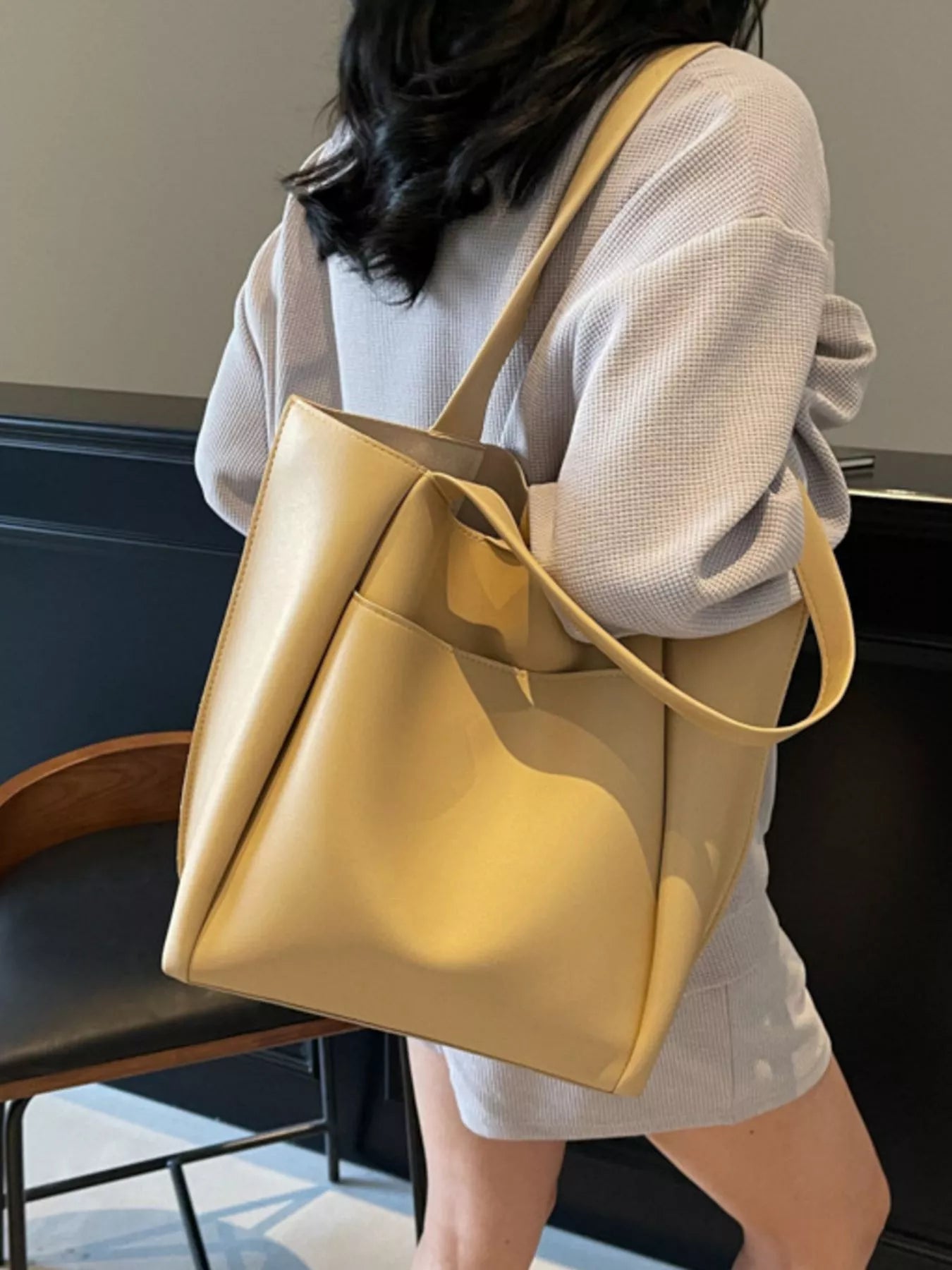 Person holding a yellow tote bag indoors