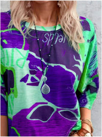Person wearing a colorful shirt with abstract patterns and a necklace.
