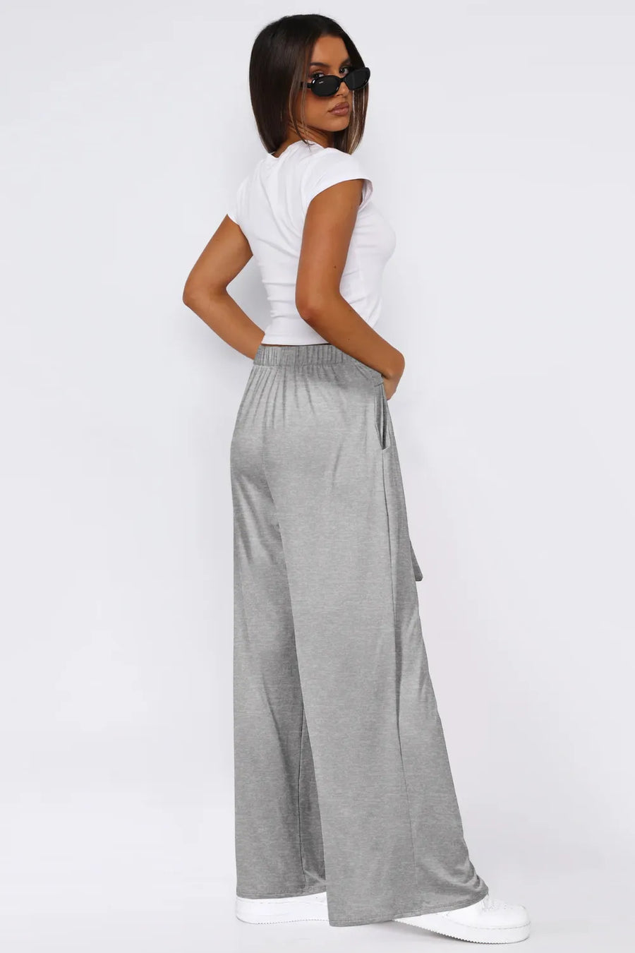 Woman wearing a white top and gray wide-leg pants on a white background