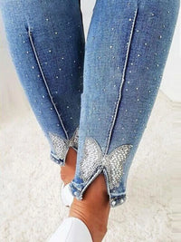 Close-up of blue jeans with rhinestone embellishments on a light background