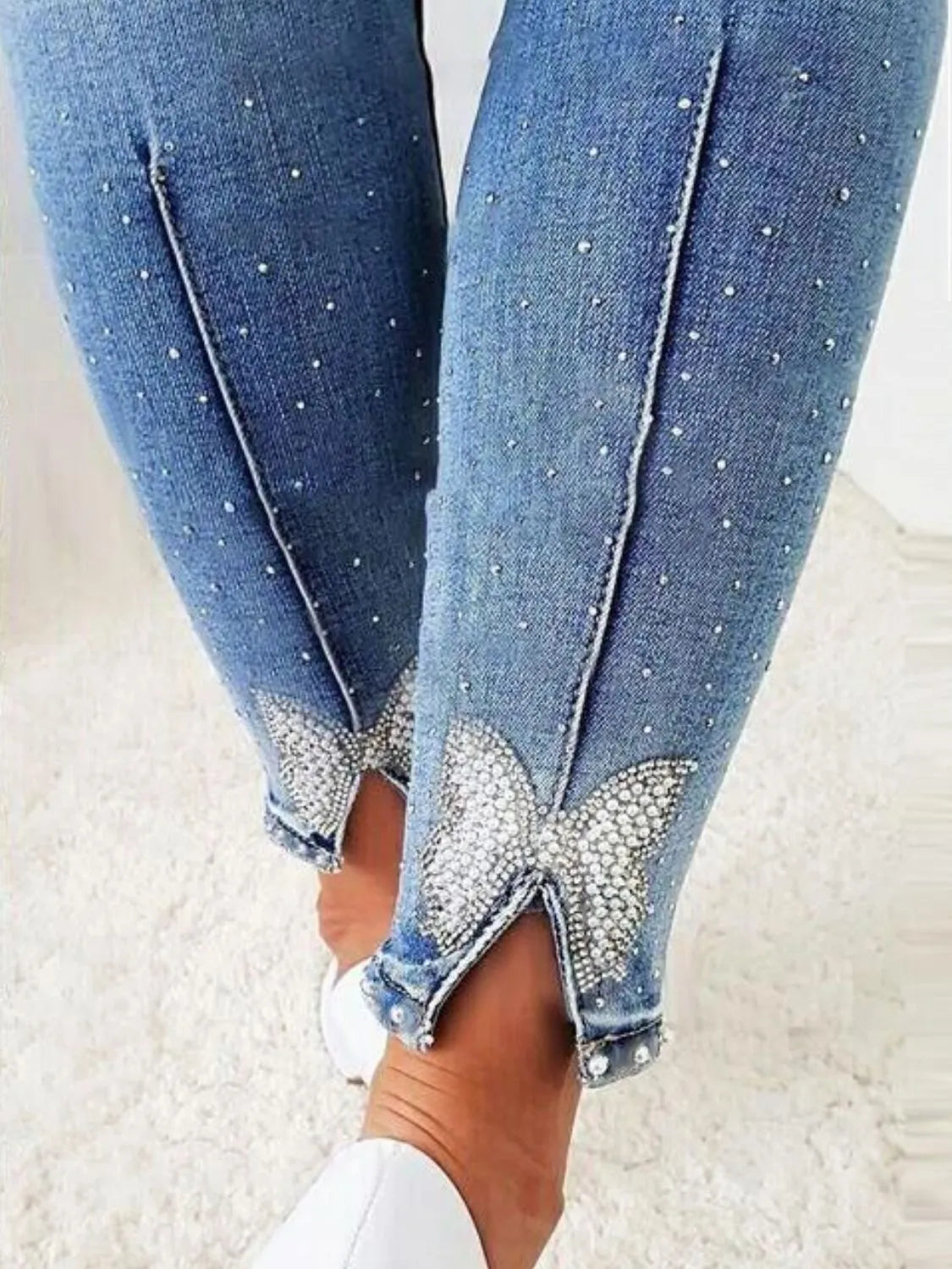 Close-up of blue jeans with rhinestone embellishments on a light background