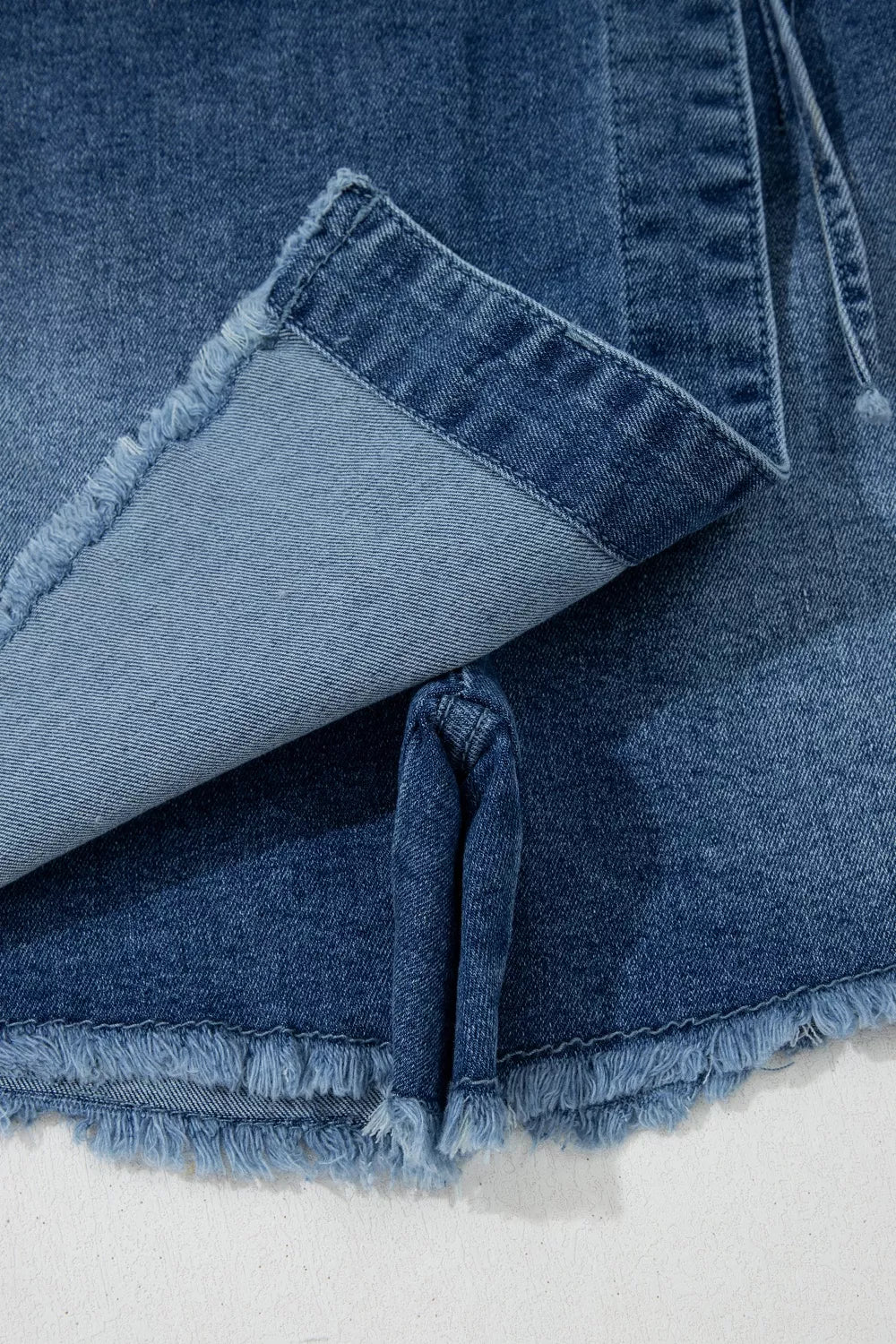 Close-up of blue denim fabric with frayed edges on a white background