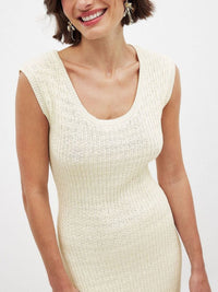 Woman wearing a white ribbed dress against a plain background