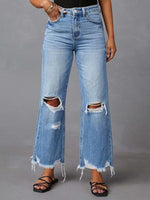 Person wearing ripped blue jeans on a gray background