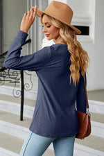 Woman wearing a navy long-sleeve top and tan hat, standing on a striped floor.