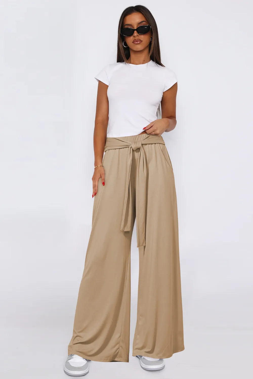 Woman wearing a white top and beige wide-leg pants on a white background