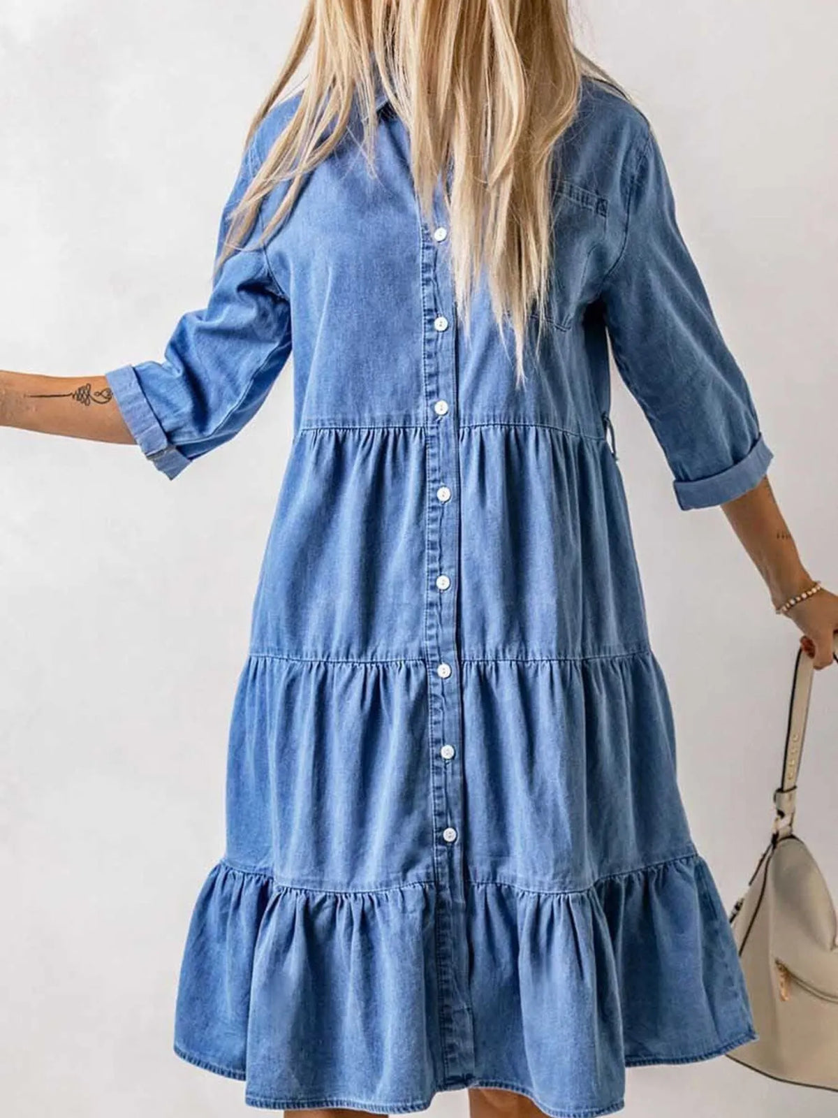 Woman wearing a blue denim dress with a plain background