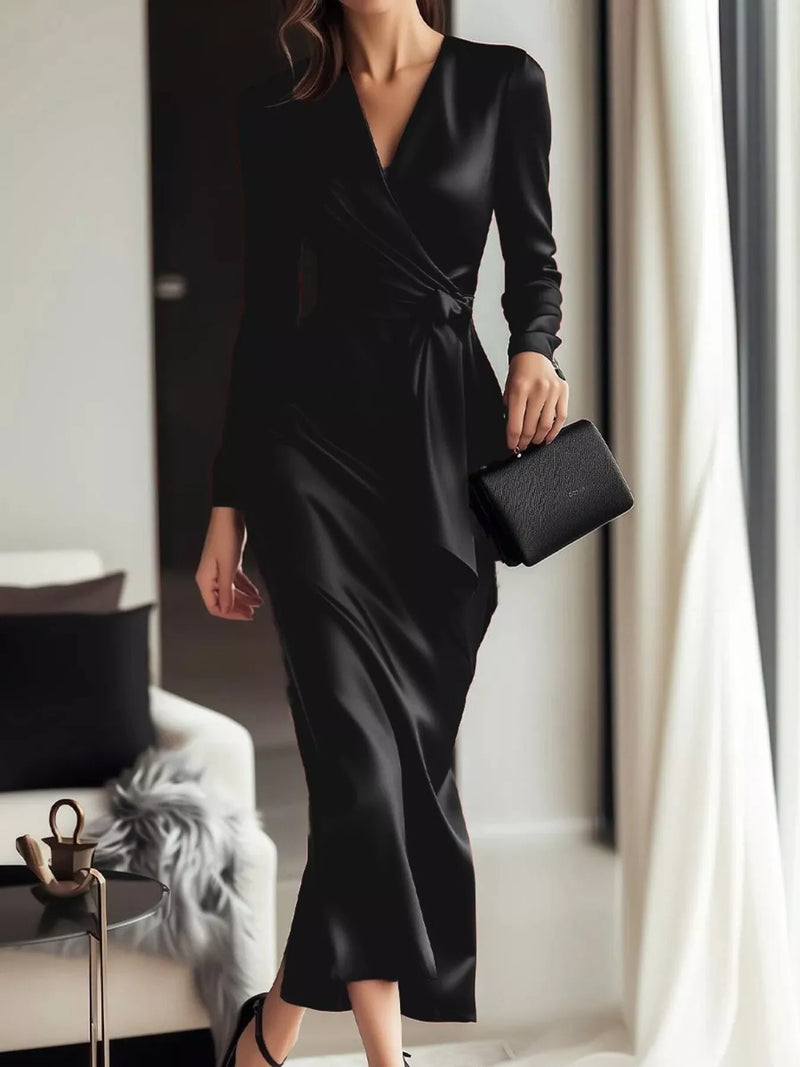Woman wearing a black dress holding a clutch in an indoor setting