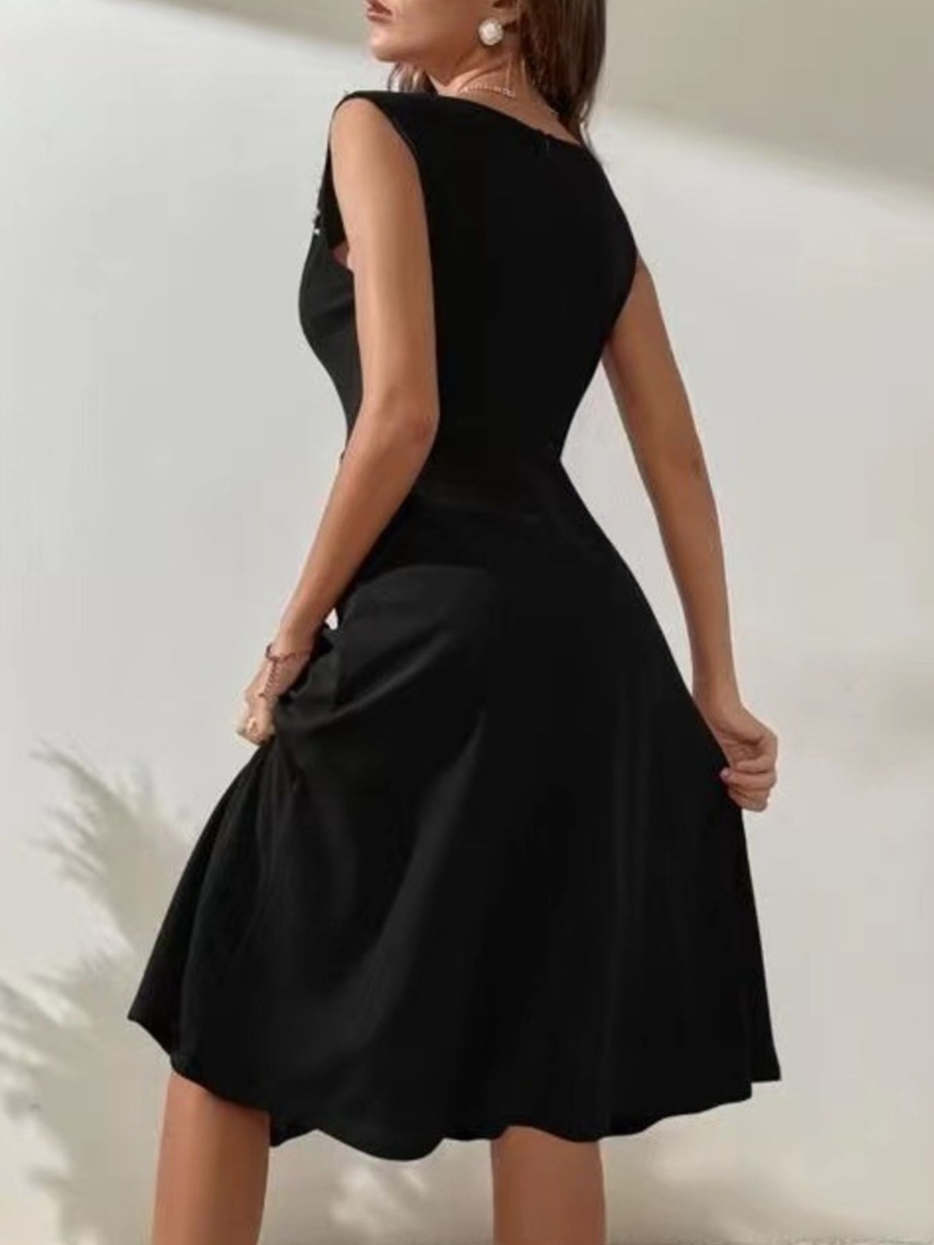 Woman wearing a black dress against a plain background