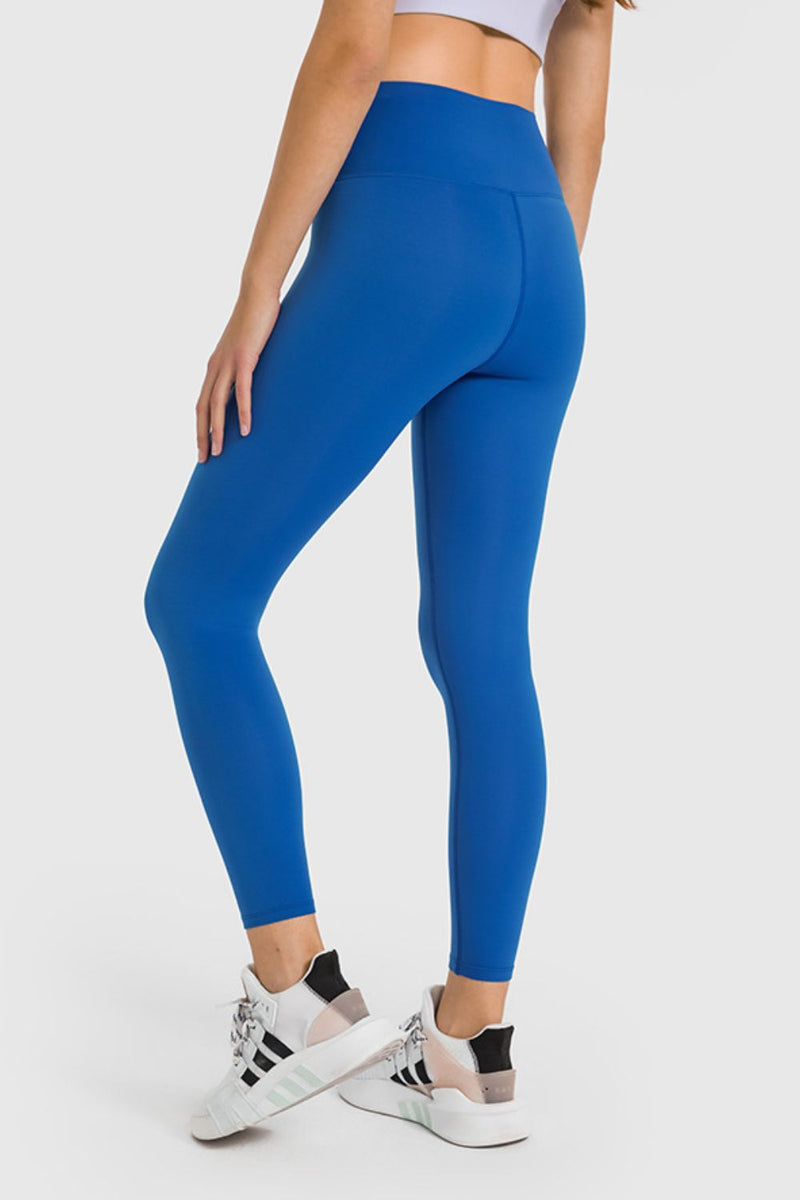 Person wearing blue leggings and white sneakers on a white background