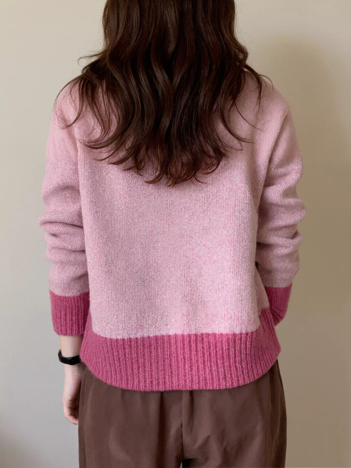 Person wearing a pink sweater with a neutral background