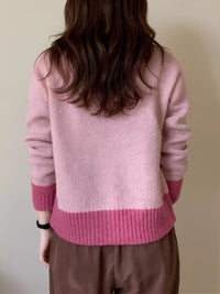 Person wearing a pink sweater with a neutral background