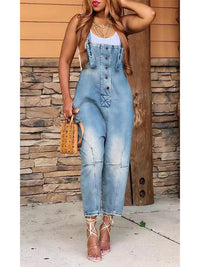 Woman wearing a denim jumpsuit standing against a stone wall.