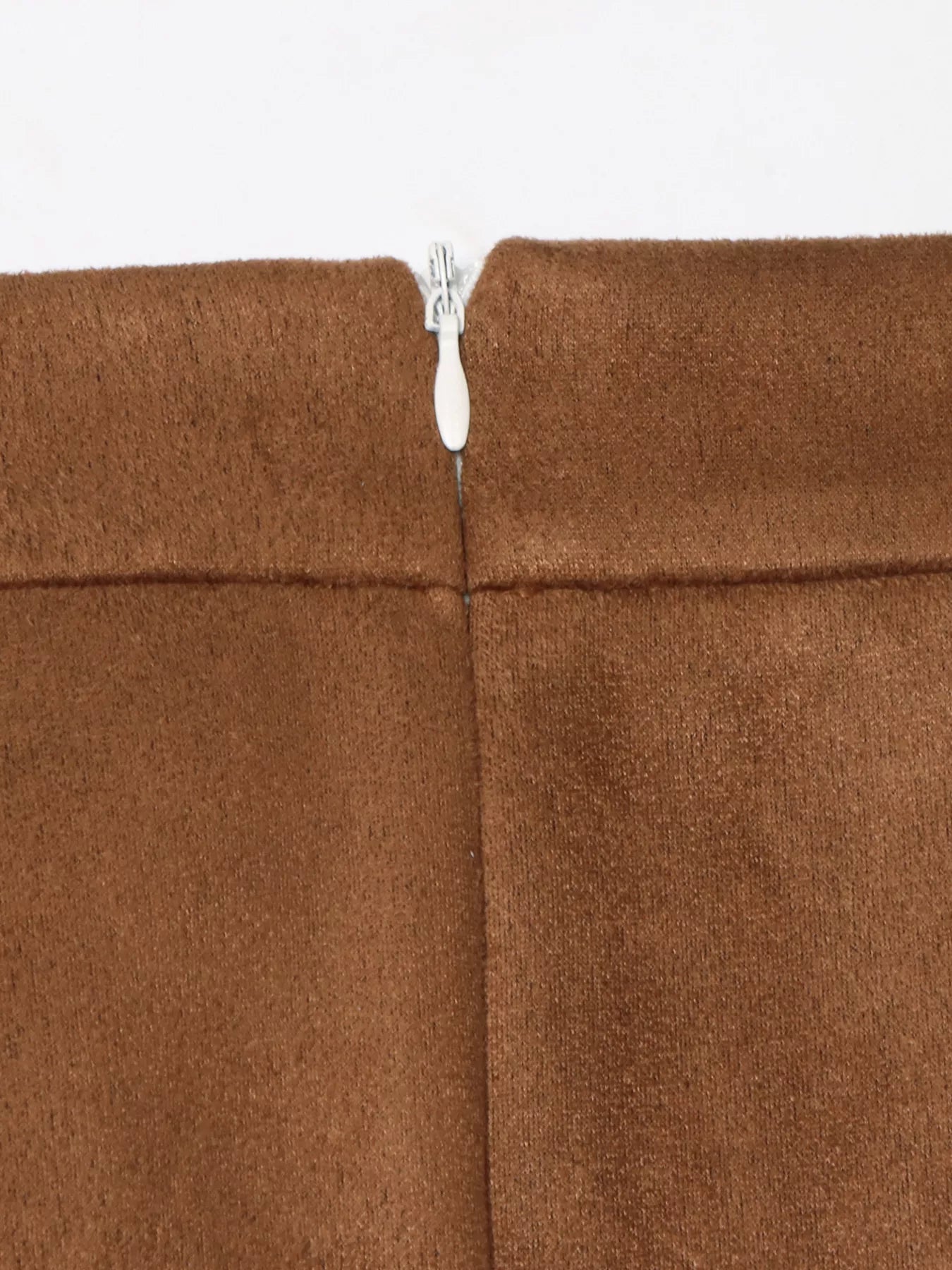 Close-up of a brown fabric with a zipper running through it on a white background