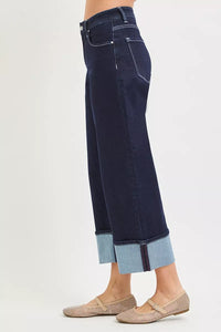 Dark blue jeans with cuffed hems on a white background