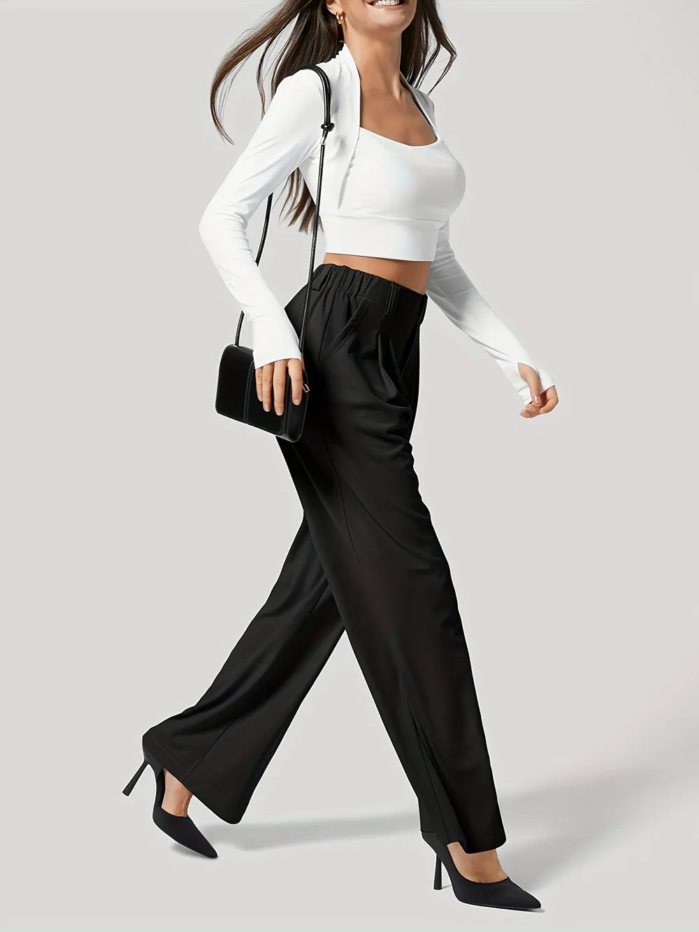 Woman wearing a white long-sleeve top and black wide-leg pants on a plain background