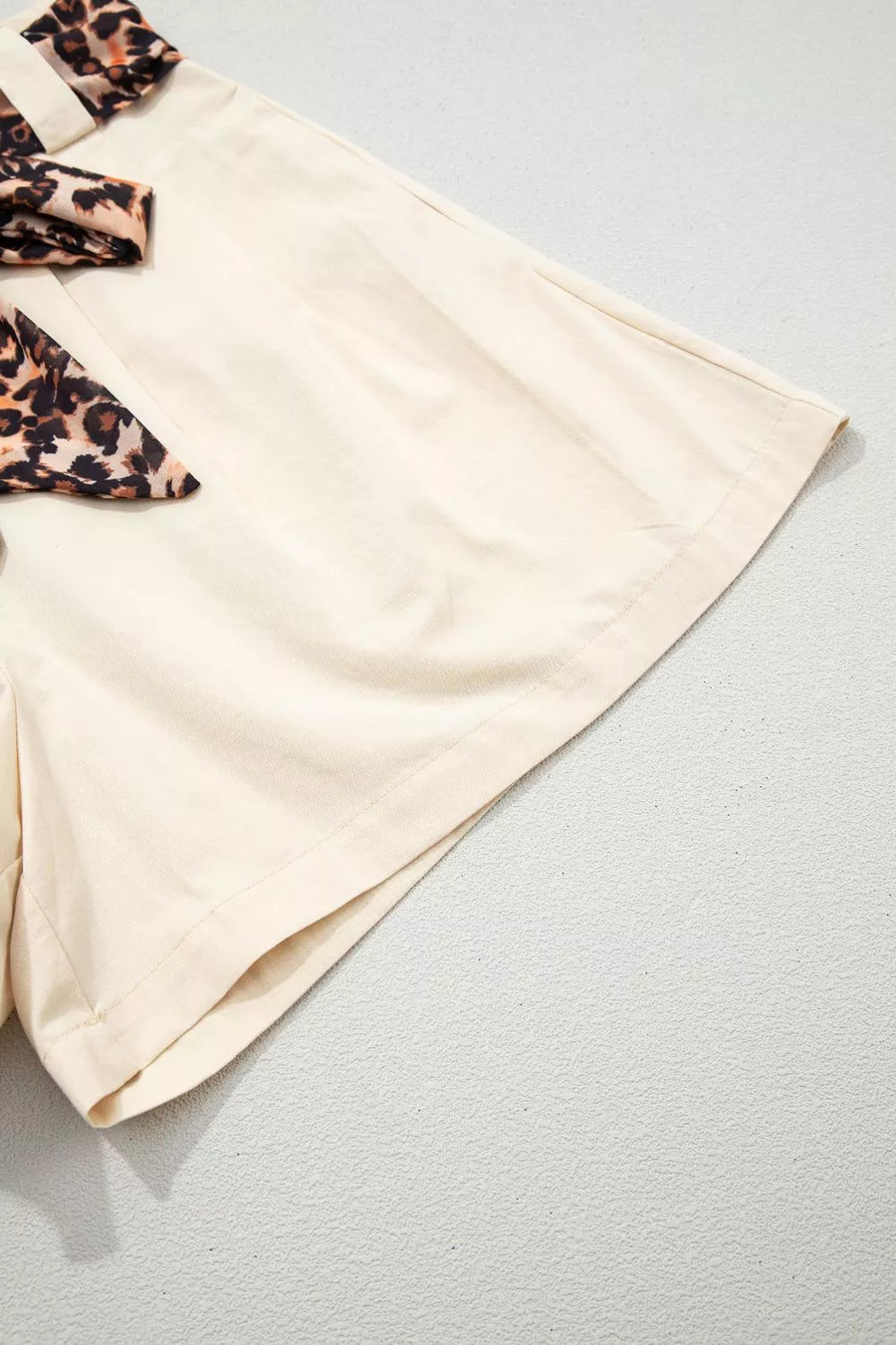 Beige shorts with leopard print accents on a light gray background