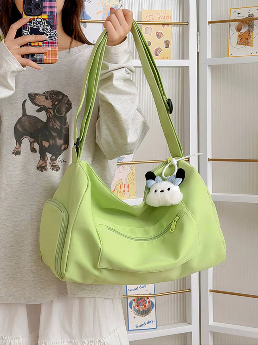 Person holding a light green handbag with a small plush toy attached, in front of a white shelf.