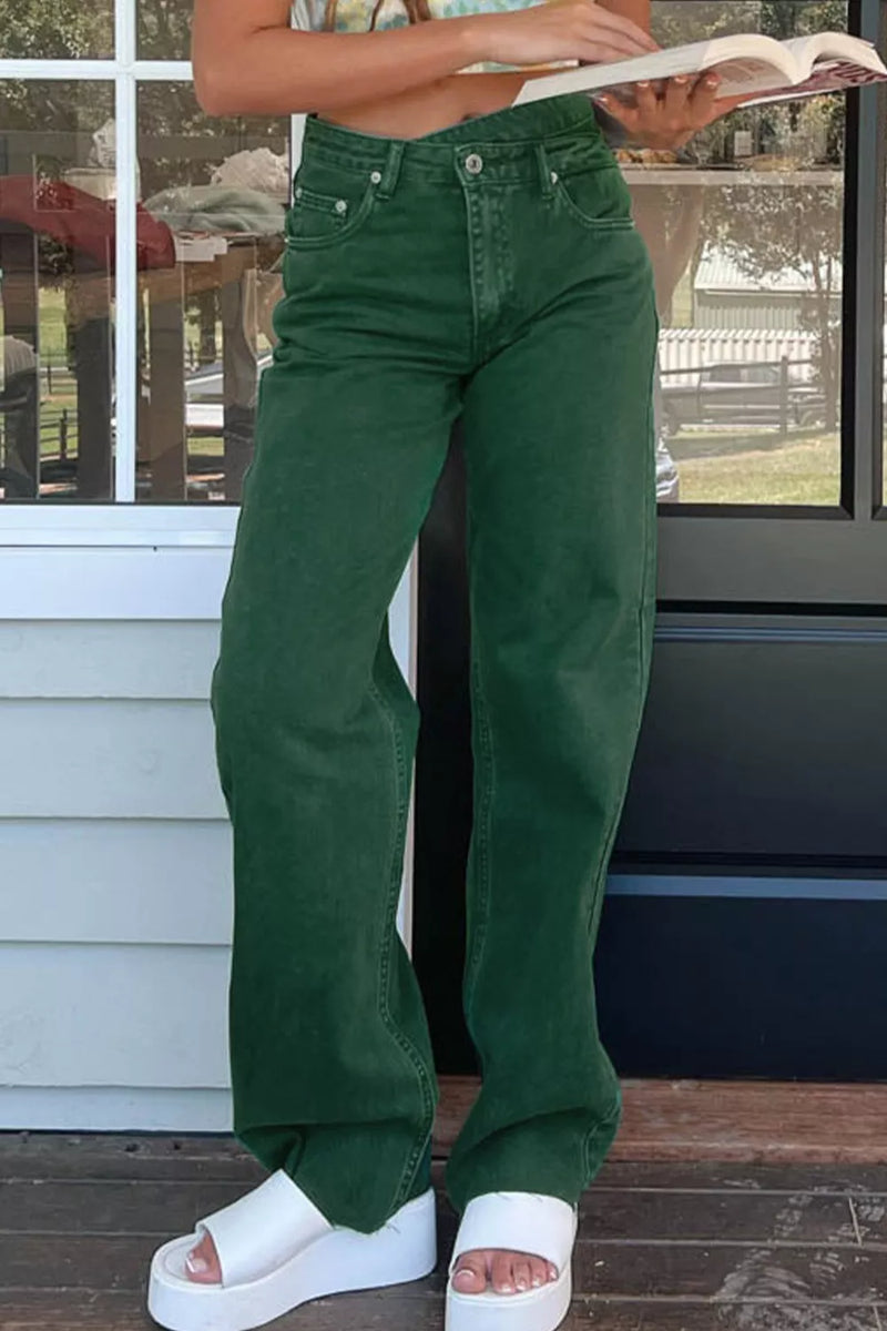 Person wearing green pants and white sandals standing on a wooden deck.