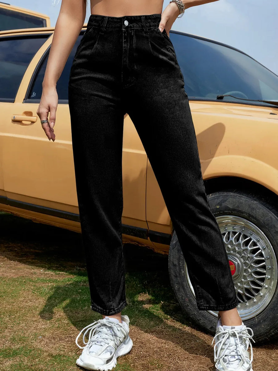 Person wearing black pants and white sneakers standing next to a yellow car.