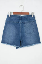 Blue denim shorts on a hanger against a white background