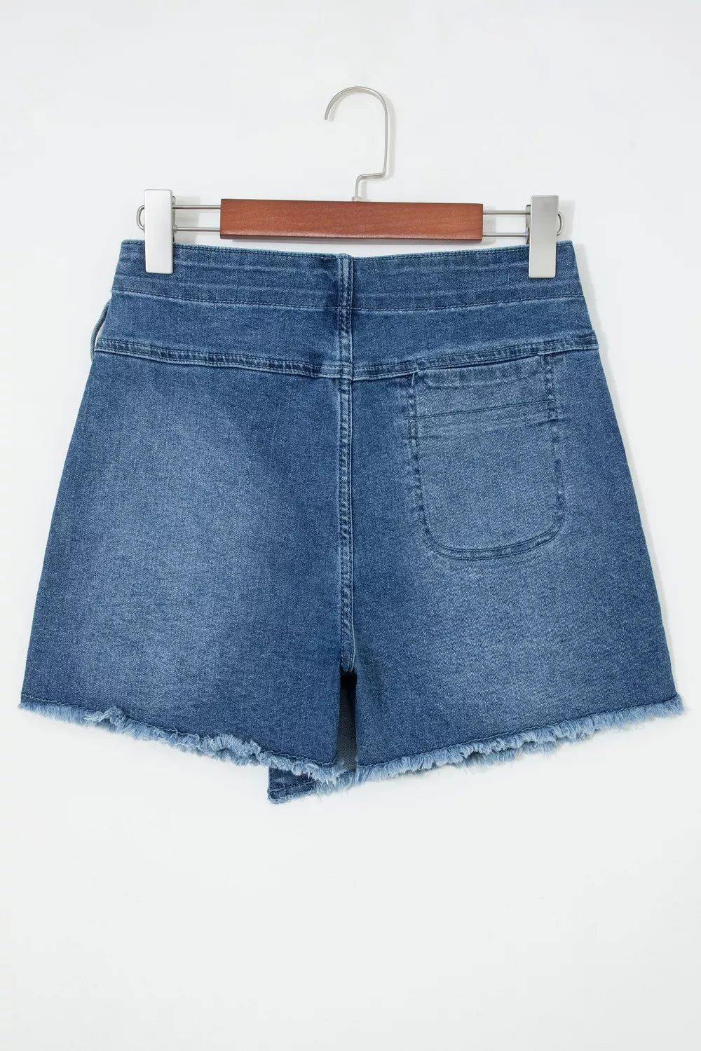 Blue denim shorts on a hanger against a white background