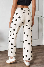 Person wearing white pants with black polka dots in a minimal indoor setting