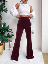 Woman wearing a white top and burgundy pants in a festive setting with a Christmas tree.