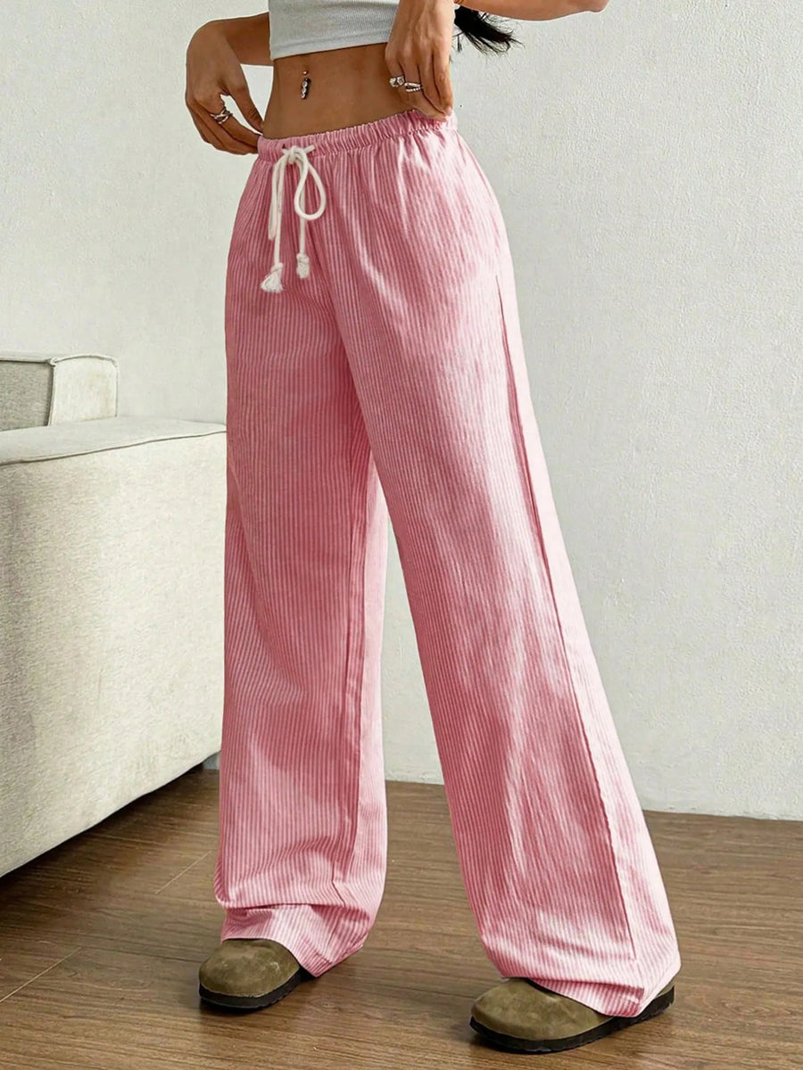 Person wearing pink striped pants in a minimal indoor setting