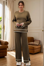 Woman wearing a green outfit standing in a room with brown furniture.