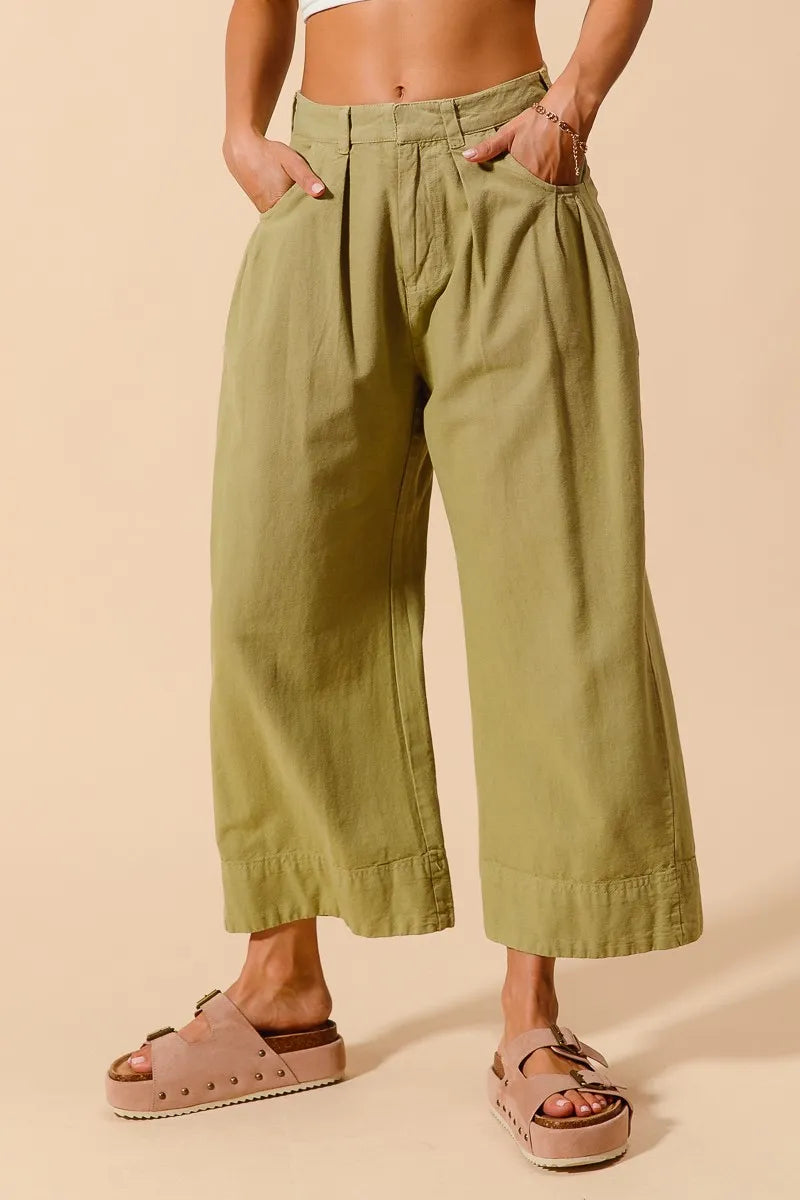 Person wearing green wide-leg pants on a beige background