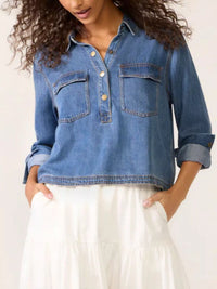 Woman wearing a blue denim shirt over a white dress on a plain background
