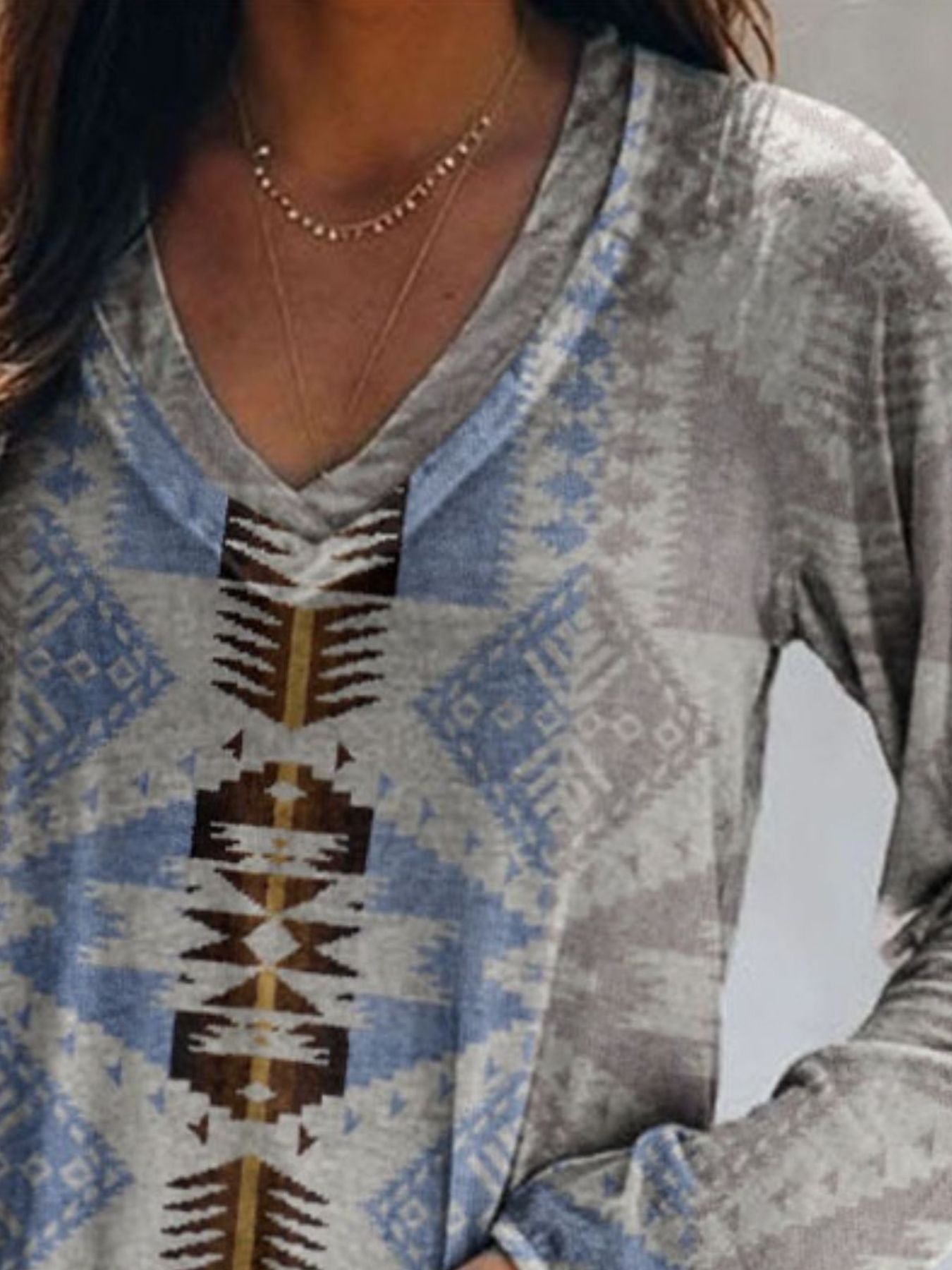Person wearing a patterned long-sleeve shirt with a neutral background