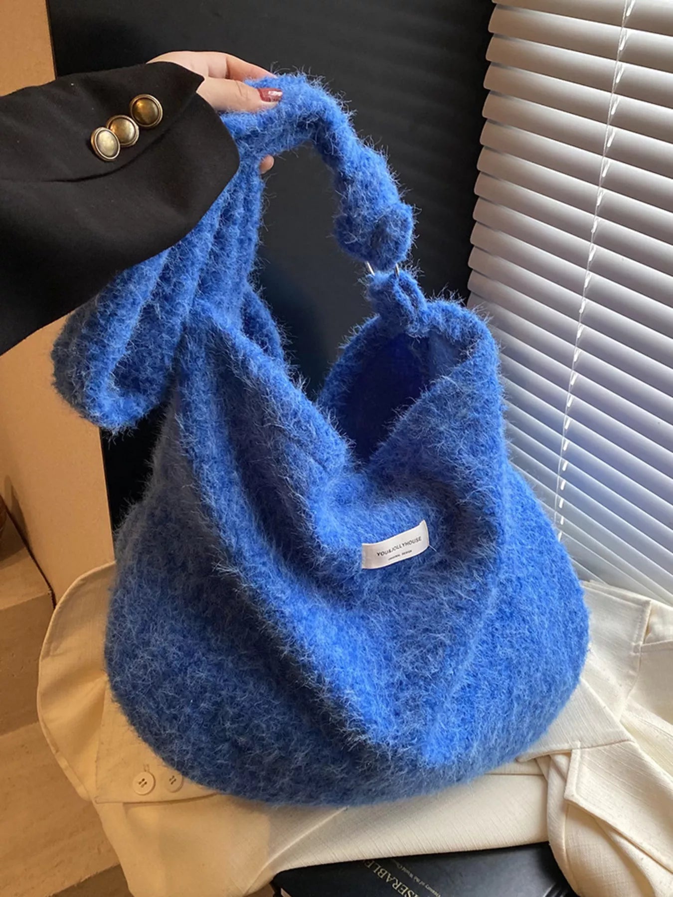 Blue fluffy handbag held by a person with a blurred background