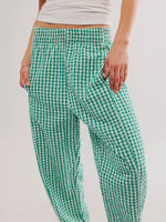 Green and white checkered pants worn by a person on a plain background