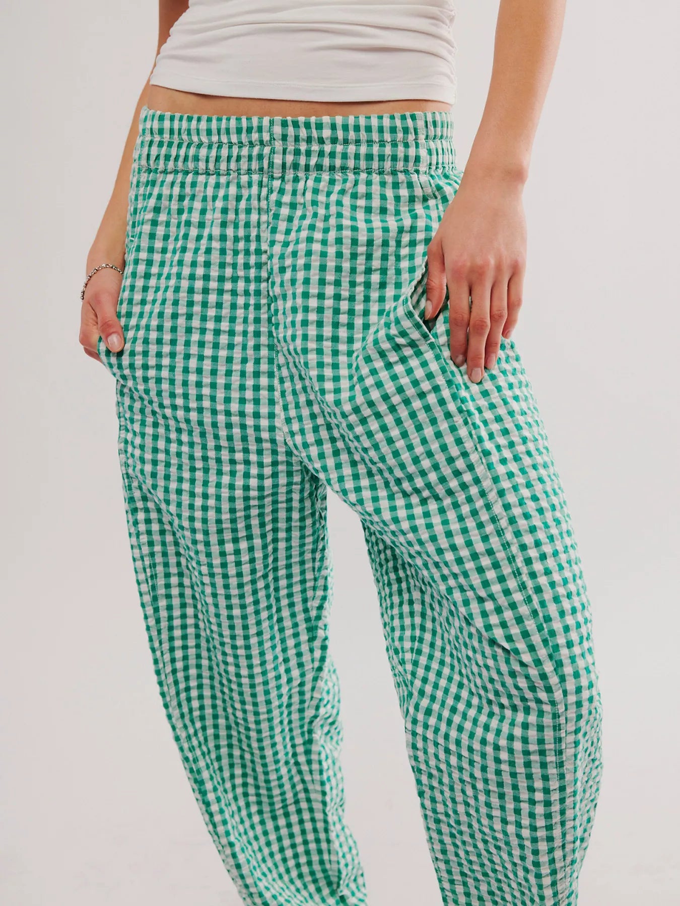 Green and white checkered pants worn by a person on a plain background