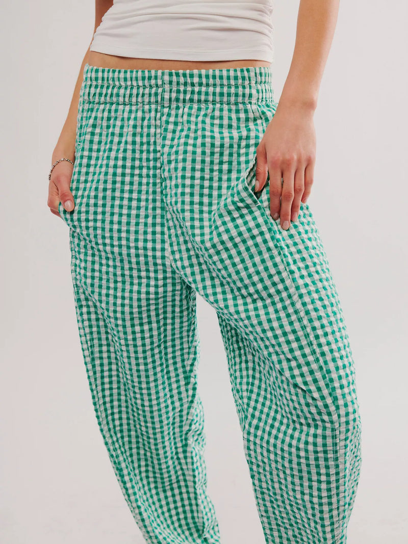 Green and white checkered pants worn by a person on a plain background