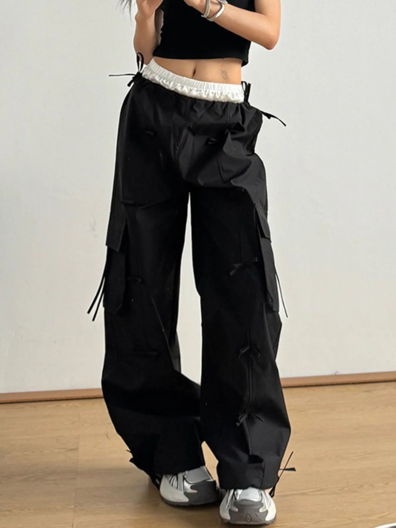 Person wearing black cargo pants with a white background