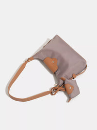 Gray and brown handbag with a strap on a white background