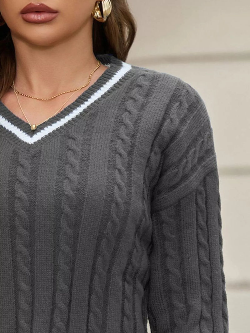 Gray cable knit sweater with a white V-neckline worn by a person.