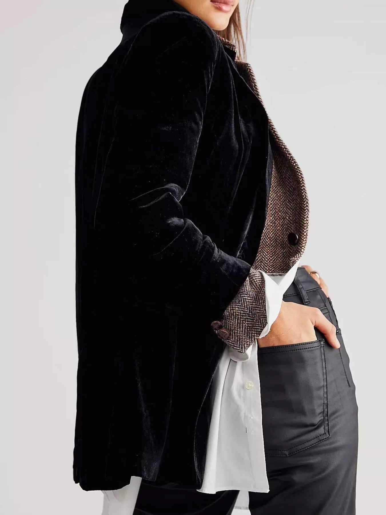 Person wearing a black coat over a plaid shirt with a plain background