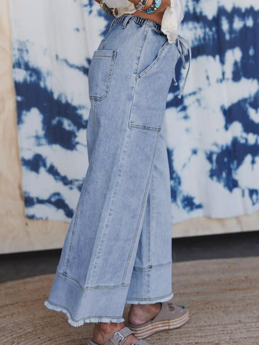 Light blue jeans worn by a person with a tie-dye wall in the background