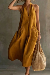 Woman wearing a mustard yellow dress holding a woven bag against a neutral background