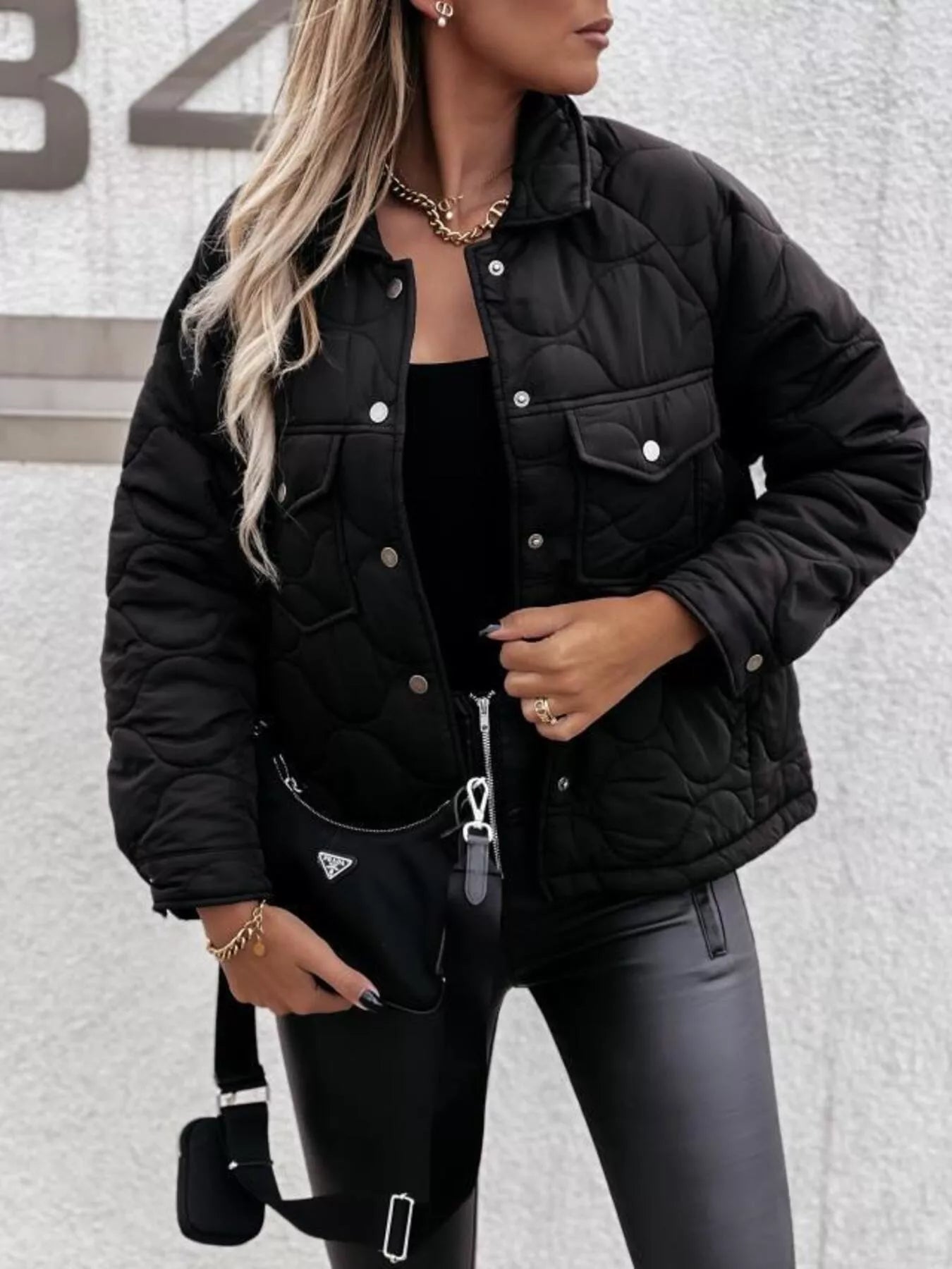 Person wearing a black quilted jacket with a neutral background