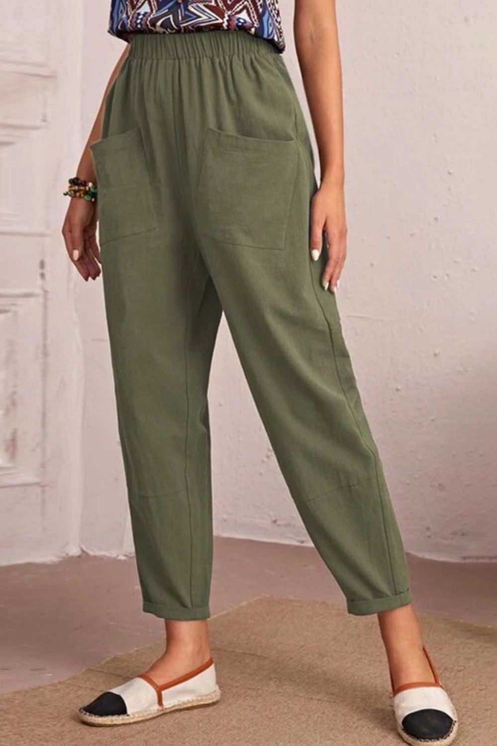 Person wearing green pants with a white wall background