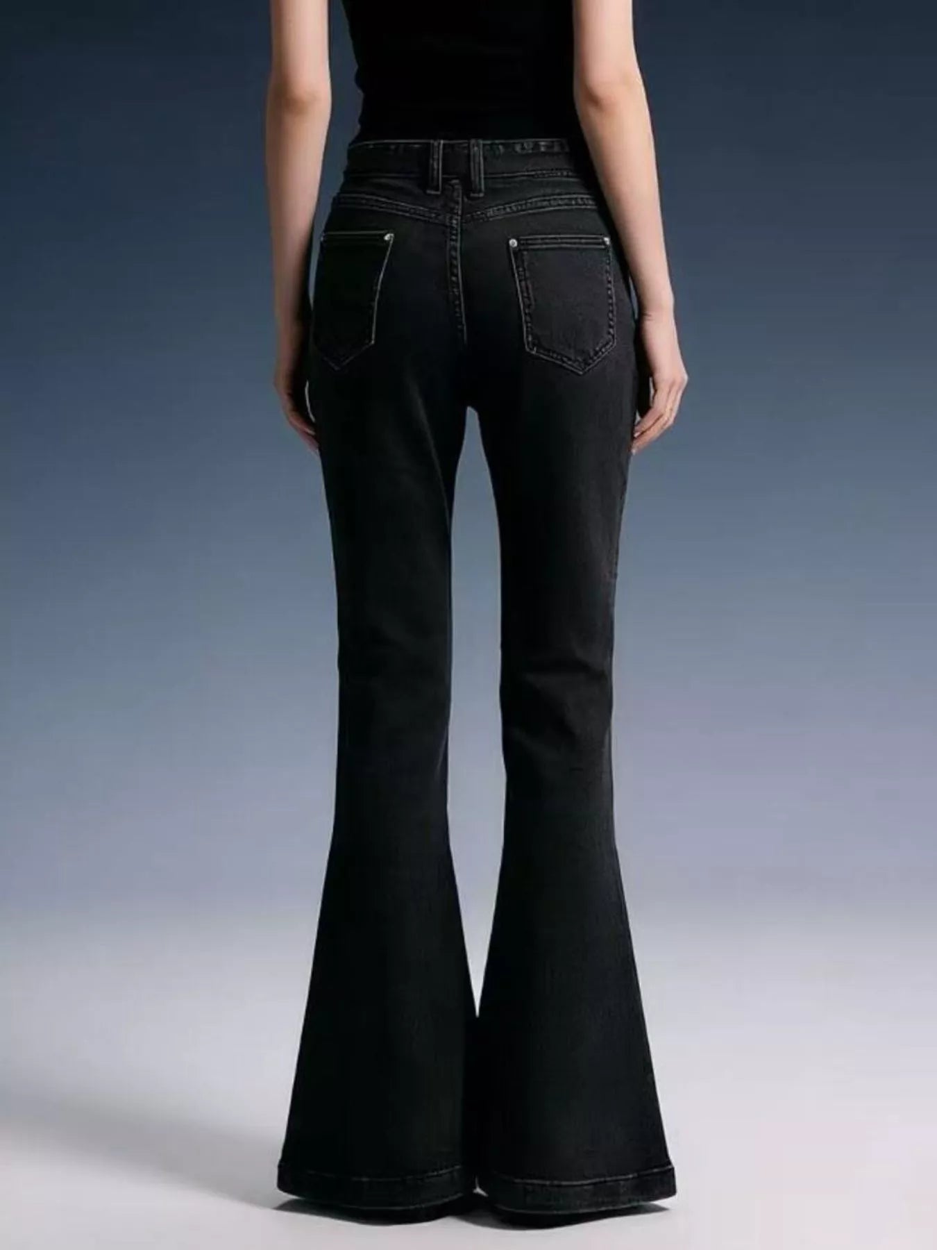 Black flared jeans worn by a person on a gradient background
