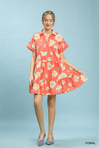 Woman wearing a coral floral dress on a light blue background