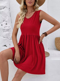 Woman wearing a red dress and straw hat against a white wall.